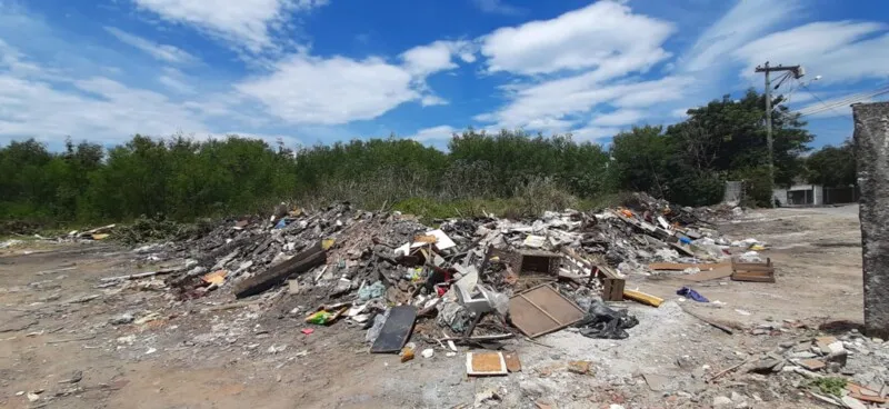 O lixo se acumula a céu aberto em um terreno do bairro