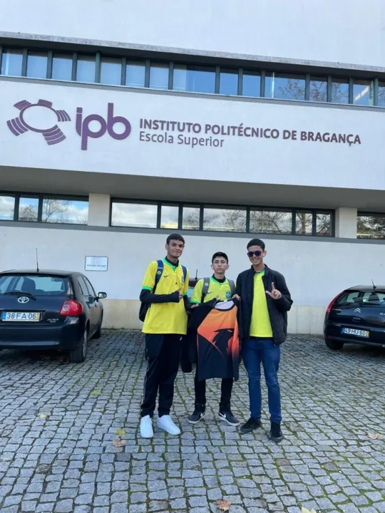 Eduardo Andrade da Conceição, Cristian Valente Monteiro e Lucas Brasil dos Santos em frente a Universidade de Bragança segurando a camisa da competição de robótica