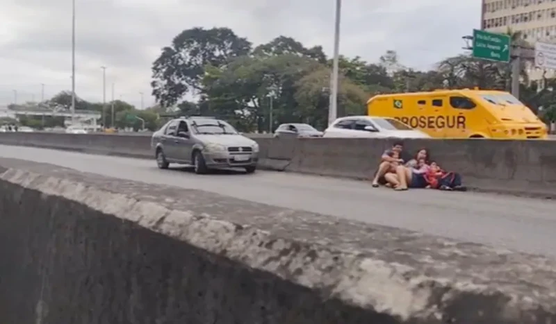 Pessoas se abrigando na mureta em meio ao tiroteio