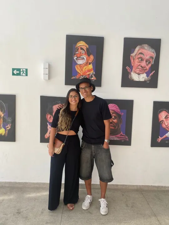 Dan ao lado de sua filha durante exposição das caricaturas no Teatro Municipal de São Gonçalo