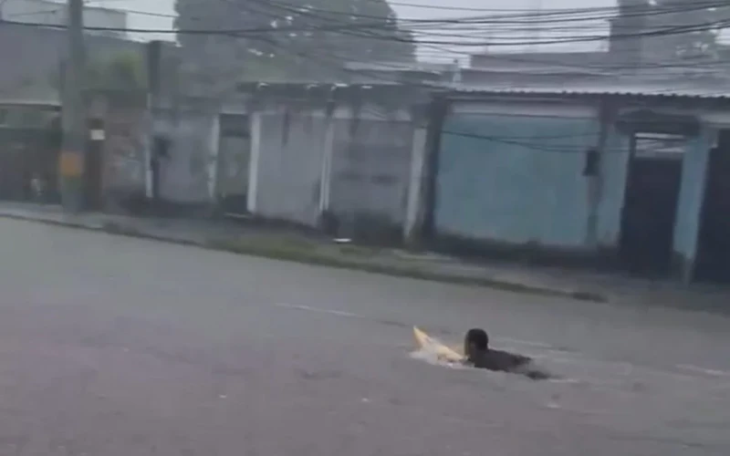 Jovem surfa em rua que transbordou o valão na Baixada Fluminense