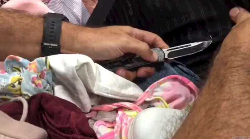 Um agente usa uma faca para cortar a mala onde estava escondida a cocaína