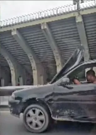 Ele tenta enxergar a pista por uma pequena fresta entre o capô e o compartimento do motor