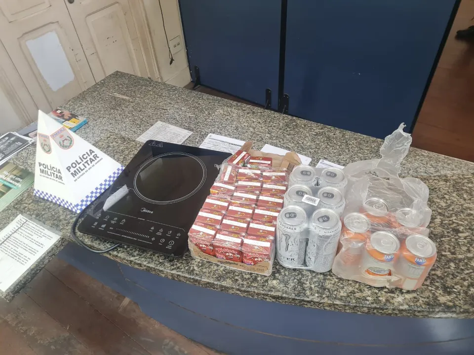 Foram apreendidos um aparelho de som; uma caixa de achocolatado; uma caixa de refrigerante em lata e uma caixa de energético