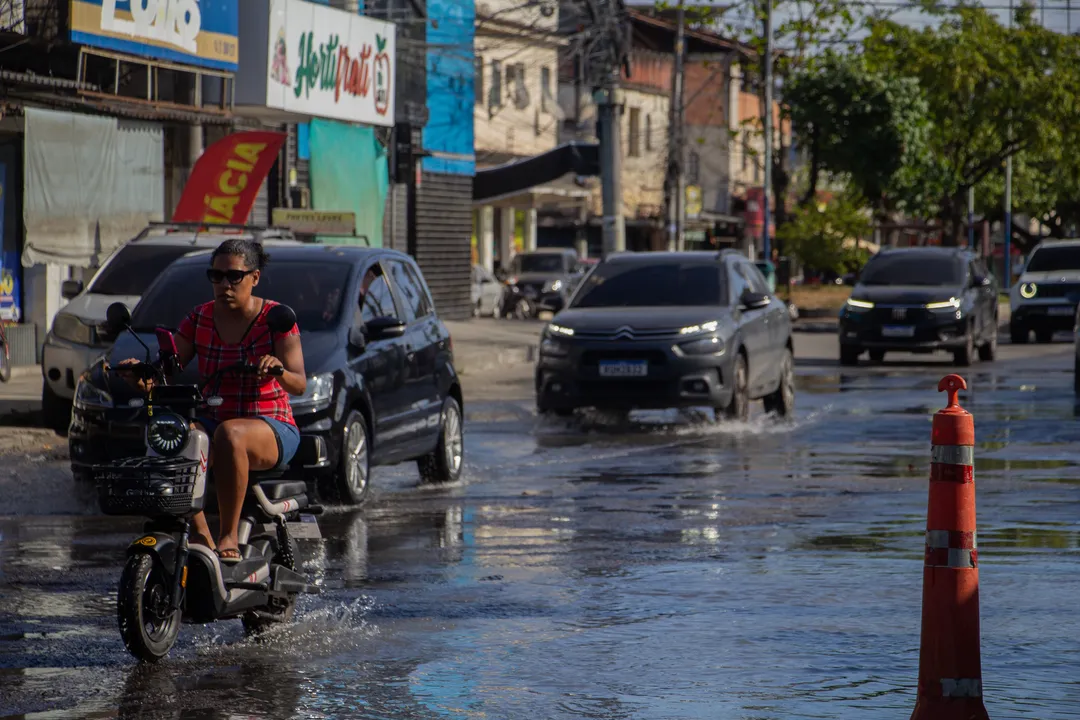 Ciclista procura espaço para passar entre poças e buracos