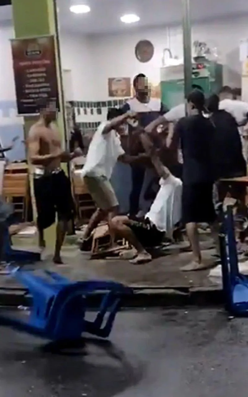No vídeo, um grupo de homens troca socos e joga cadeiras de plástico nas outras pessoas