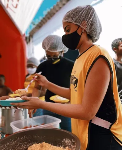 Voluntários servem a alimentação das crianças durante as atividades