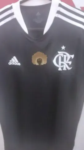 Blusa tem o desenho de uma pessoa negra entre o símbolo do clube e da Adidas