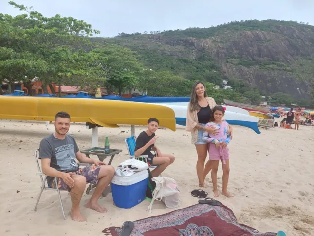 Pais e filhos aproveitam tempo ameno para relaxar na praia.