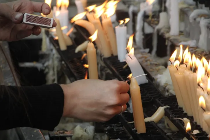 Fiéis acendem velas para pedir e agradecer, conforme a tradição