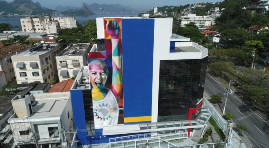 A obra de Kobra mostra uma mulher com o braço erguido, como quem festeja ter vencido a luta contra o câncer