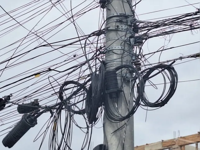 Poste com fios arrebentados e enrolados