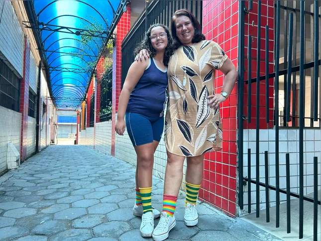 Cristiane e sua filha Sarah mostrando orgulho e apoio à inclusão no Dia Internacional da Síndrome de Down com as meias coloridas