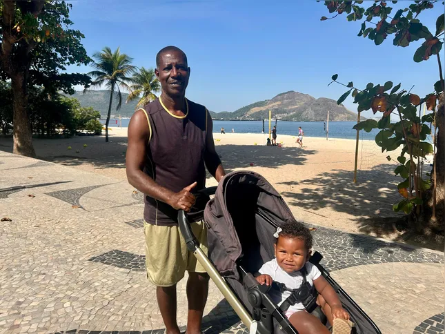 Carlos Alberto aproveita o calor fora de época para caminhar com a neta pela praia