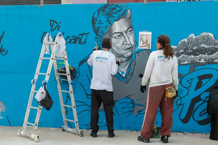 Artistas pintando Di Cavalcante, uma das personalidades homenageadas no painel