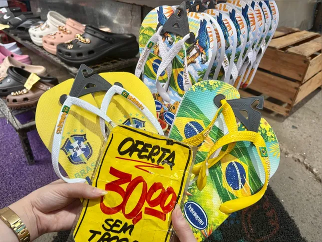 Os chinelos são personalizados com imagens da bandeira do Brasil e o emblema da CBF