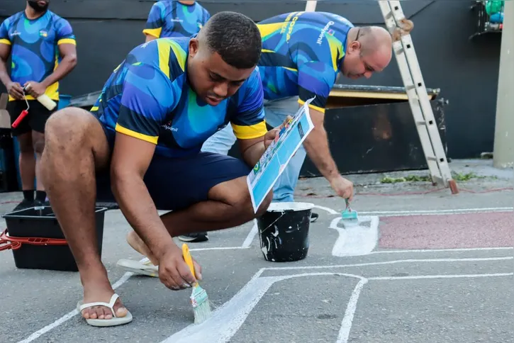 Moradores do bairro Santa Catarina reunidos para pintar a rua com decorações para a Copa