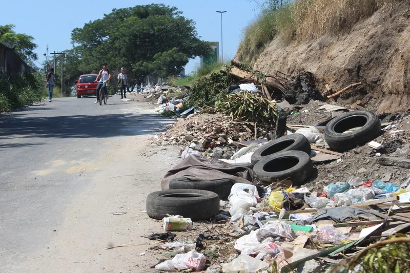 Lixo, inclusive pneus, copos e latas, é jogado, diariamente, em uma área de avenida do Laranjal