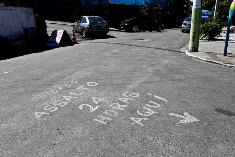 Na Brasilândia, moradores pintaram em pedaço de madeira, um aviso como alerta para assaltos