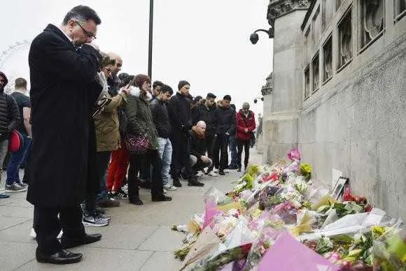 Pessoas observam homenagens às vítimas do atentado na ponte de Westminster, em Londres