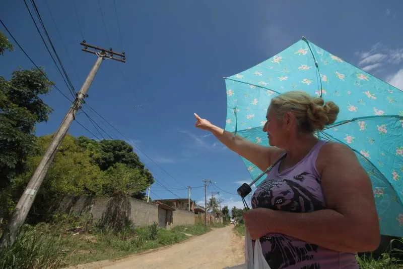 Moradora mostra a situação de um dos postes que não tem lâmpada e está completamente torto