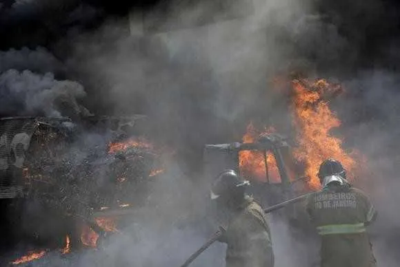 Bombeiros apagam chamas de caminhão queimado perto da Cidade Alta, no Rio de Janeiro, durante confronto de facções criminosas rivais