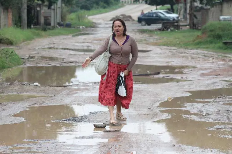 A cuidadora Nilceli de Azevedo mostra o estado em que a Rua L fica em dias de chuva forte