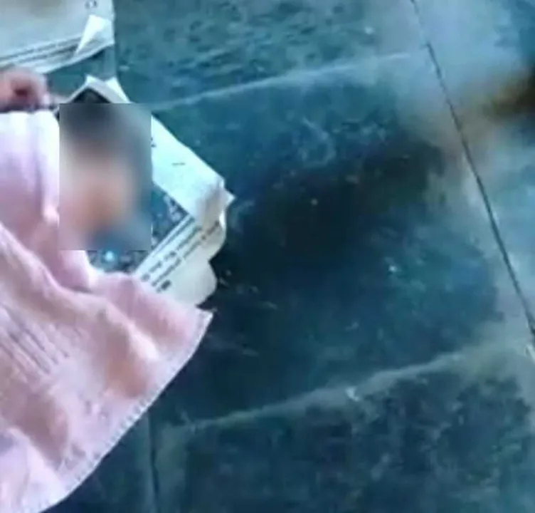 Casal passava em frente ao estabelecimento comercial quando um cachorro latiu, chamando a atenção para a criança que estava enrolado num jornal