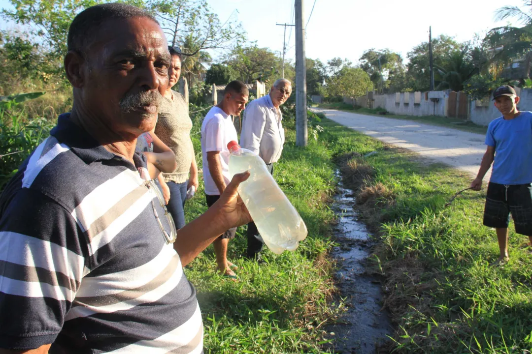 O assistente administrativo Gilmar Soares mostra a garrafa com a água suja que eles têm acesso