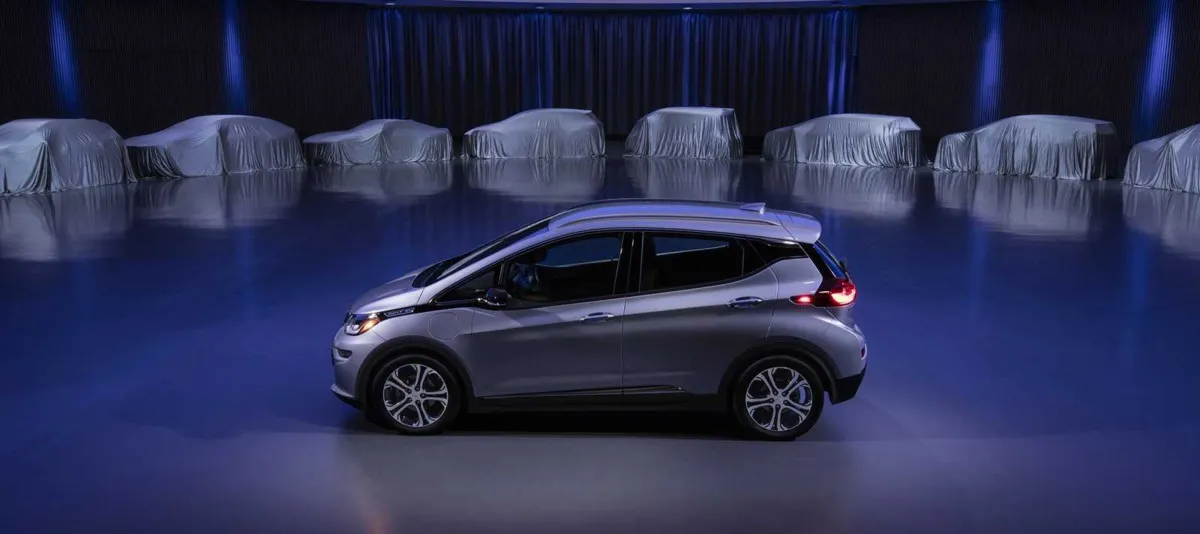 Ao fundo, os modelos cobertos que ainda serão anunciados, em experiências baseadas no Chevrolet Bolt