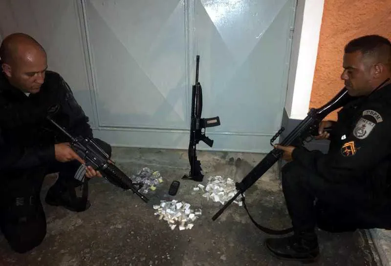 Os policiais militares mostram o fuzil e as drogas que foram apreendidas durante a operação na comunidade de SG