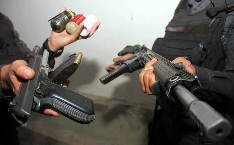 Policiais exibem as armas que estavam em poder dos acusados que foram baleados no local