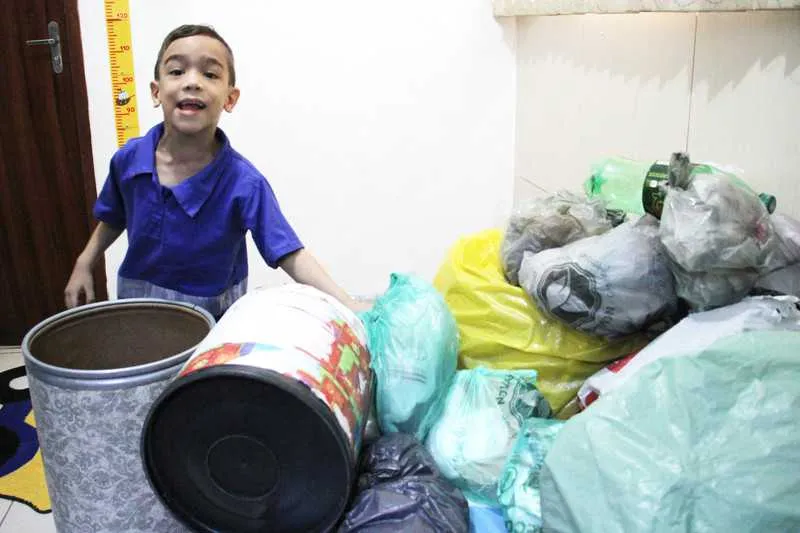 A cama do menino Brayan também faz parte da brincadeira, virando uma 'caçamba de lixo'