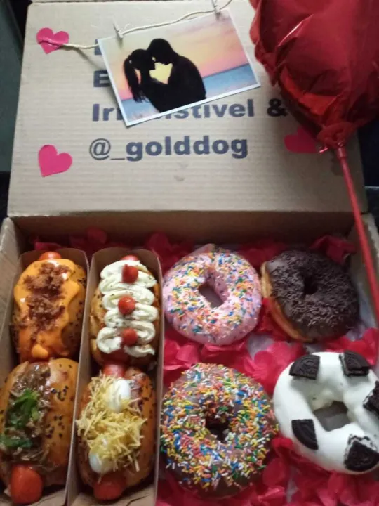 A caixa decorada vem com mini cachorros quentes e três sabores de donuts