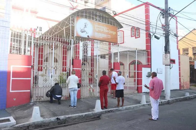Mesmo com portas fechadas, fieis ainda vão à porta da Igreja de São Jorge fazer suas preces