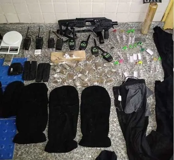 Junto com as armas e as drogas, foram encontradas tocas e fardas pretas 